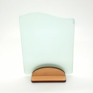 May include: A frosted glass picture frame with a wavy top edge, standing on a wooden base.
