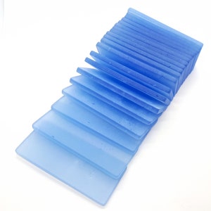 May include: A stack of light blue glass coasters. The coasters are rectangular and have a frosted finish.