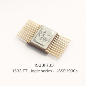 Puede incluir: Circuito integrado 1533IR33 de la serie lógica TTL, de la URSS de los años 90. El componente rectangular tiene una parte superior plateada con texto y pines dorados que se extienden por ambos lados.