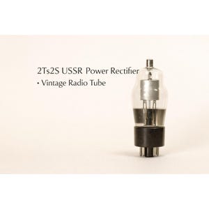 May include: A white ceramic mug with a black handle and the text "But First, Coffee" in a bold, black font. The mug is set against a blurred background, suggesting a cozy setting.