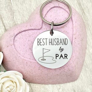 May include: Silver key chain with a round tag that says "Best Husband by Par" with a golf flag and hole graphic.