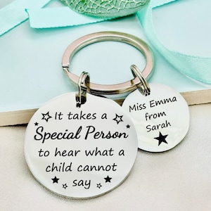 May include: Two silver keychains with a star design. One keychain says "It takes a Special Person to hear what a child cannot say." The other keychain says "Miss Emma from Sarah".