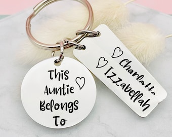 May include: Silver keychain with two tags. The round tag says "This Auntie Belongs To" with a heart. The rectangular tag says "Charlotte" and "Izabella" with hearts.