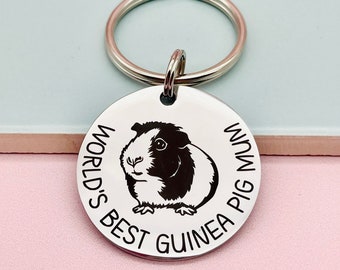 May include: A silver key chain with a round tag that says "World's Best Guinea Pig Mum". The tag has a black and white guinea pig illustration.