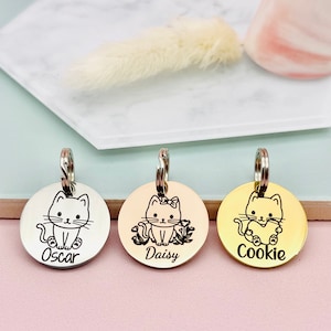 May include: Three round pet tags with cat illustrations and names. The tags are silver, gold, and rose gold. Each tag has a different cat design and name: Oscar, Daisy, and Cookie. The tags have a silver ring for attachment.