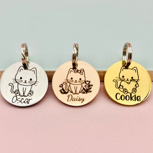 May include: Three round silver, rose gold, and gold pet ID tags with engraved cat illustrations and names "Oscar", "Daisy", and "Cookie".