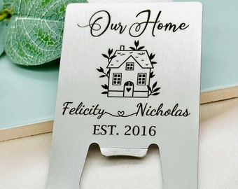 May include: Silver bottle opener with a house design and the text "Our Home Felicity Nicholas EST. 2016".