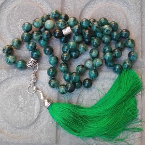 Puede incluir: Un collar mala de jade verde con un borla verde. El collar está hecho de cuentas redondas y tiene un dije de plata con una cabeza de Buda.