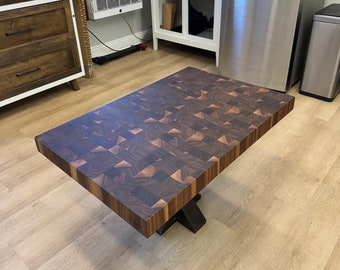 May include: A large, rectangular, dark brown wooden chopping board with a checkered pattern. The board is sitting on a wooden floor and has a black metal base.
