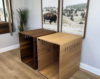 May include: Two wooden storage cubes with open sides and cutouts. The cube on the left is dark brown wood and the cube on the right is light brown wood.