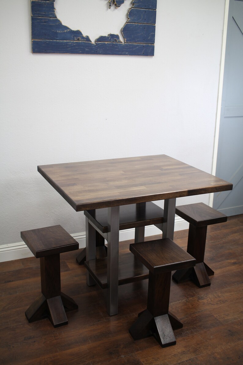 May include: A square wooden table with a metal frame and four matching wooden stools. The table has a dark brown finish and the stools have a slightly lighter brown finish. The table has a shelf underneath the tabletop.