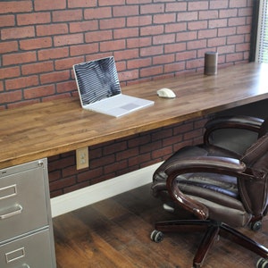 May include: A wooden desk with a metal file cabinet and a brown leather office chair. A laptop computer is on the desk with a white wireless mouse.