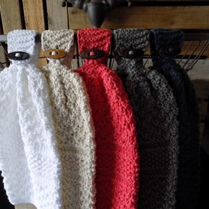 May include: Five knitted dish towels hanging on a rack. The towels are in white, beige, coral, gray, and teal.