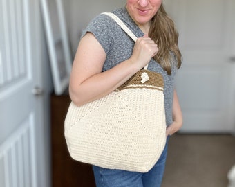 May include: A crocheted tote bag with a brown and white striped handle. The bag is made with a white yarn and has a brown stripe around the top.