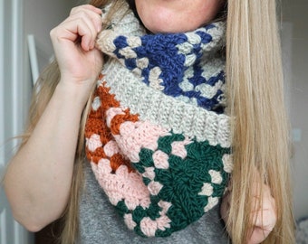 May include: A colourful crocheted cowl with a geometric pattern in shades of blue, green, pink, orange, and white.