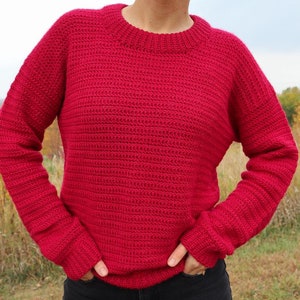 May include: A red crocheted sweater with long sleeves and a crew neck.