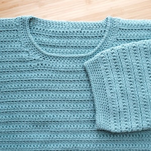 May include: A light blue crocheted top with a v-neck and short sleeves.