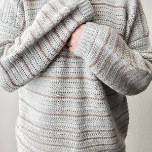 May include: A grey and brown striped crocheted sweater with a relaxed fit.