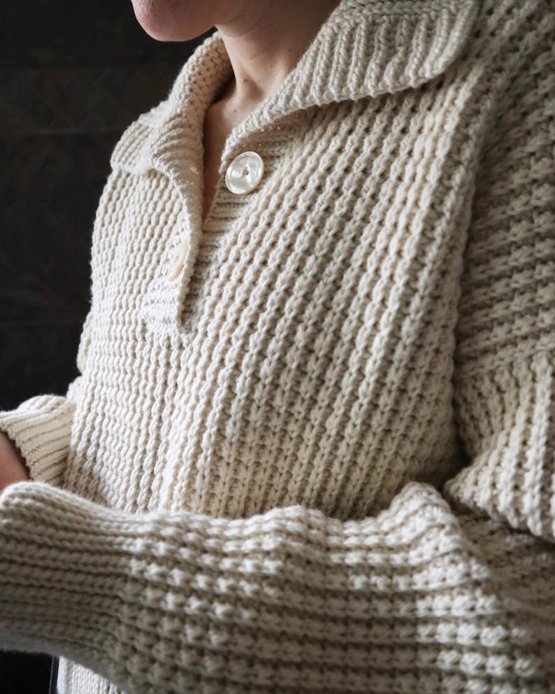 May include: A cream-colored knitted cardigan with a button closure and a ribbed texture.
