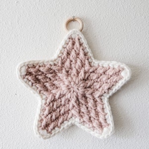 May include: A pink and white crocheted star with a wooden ring for hanging.
