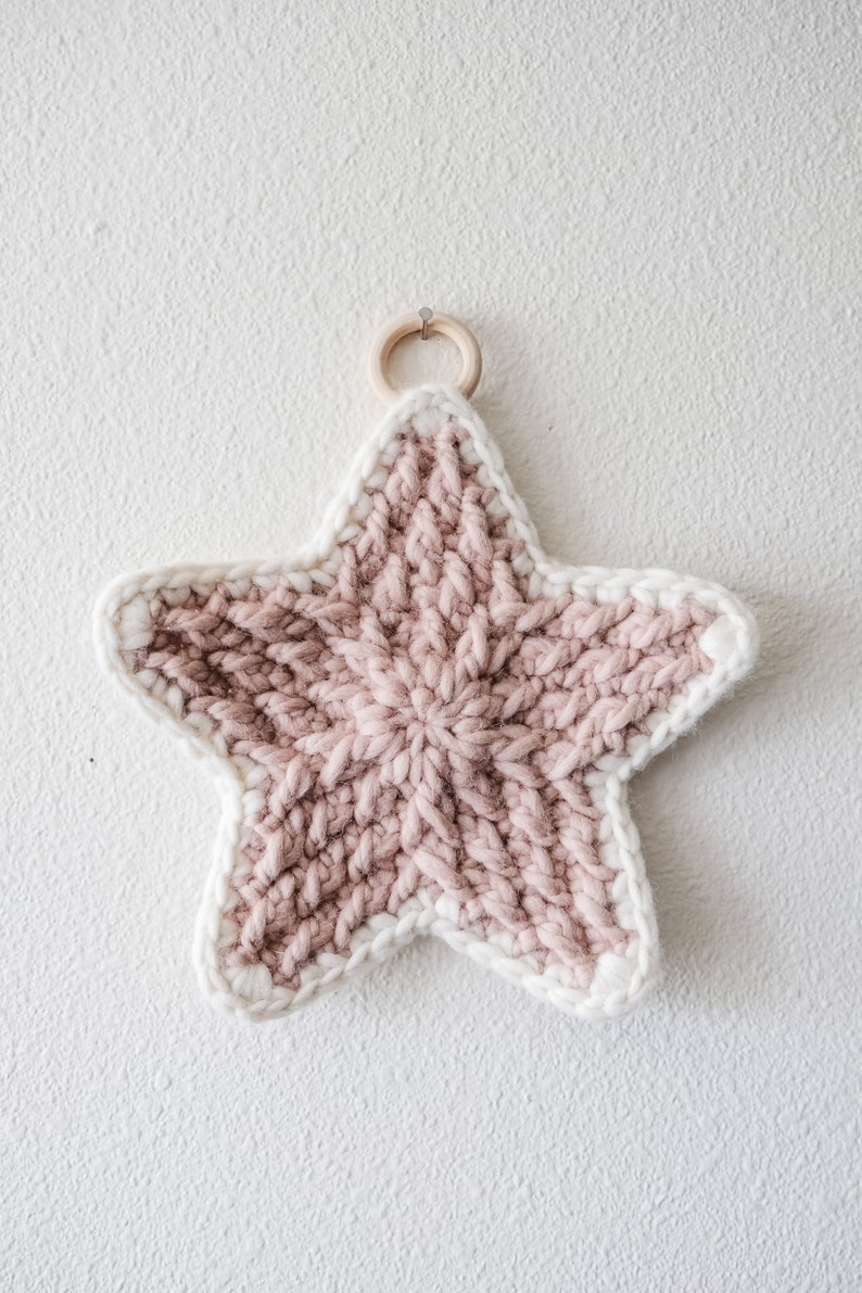May include: A pink and white crocheted star with a wooden ring for hanging.