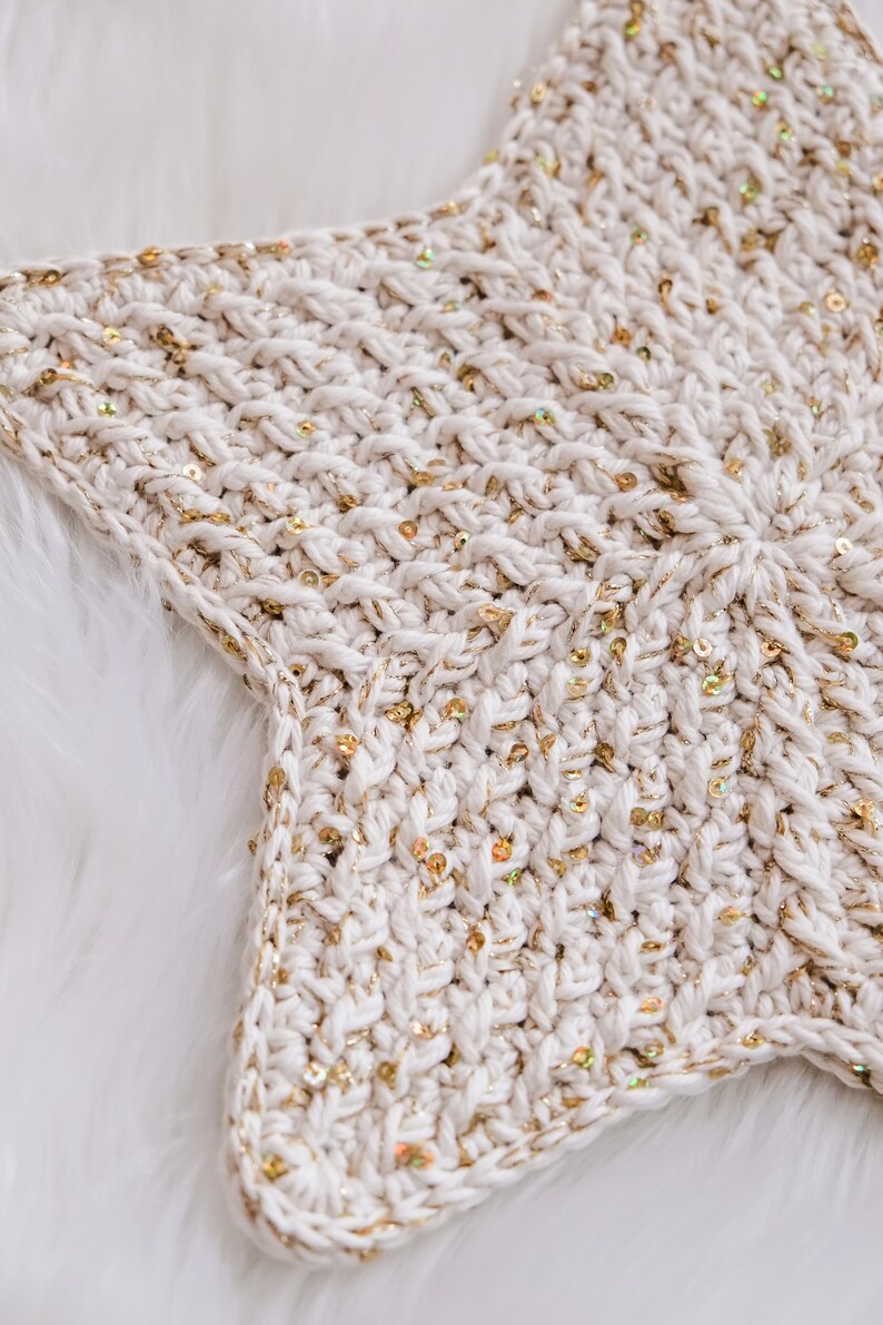 May include: A white crocheted star with gold sequins. The star is a handmade home decor item.