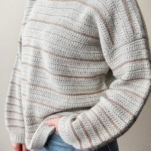 May include: A grey and brown striped crocheted sweater with long sleeves.