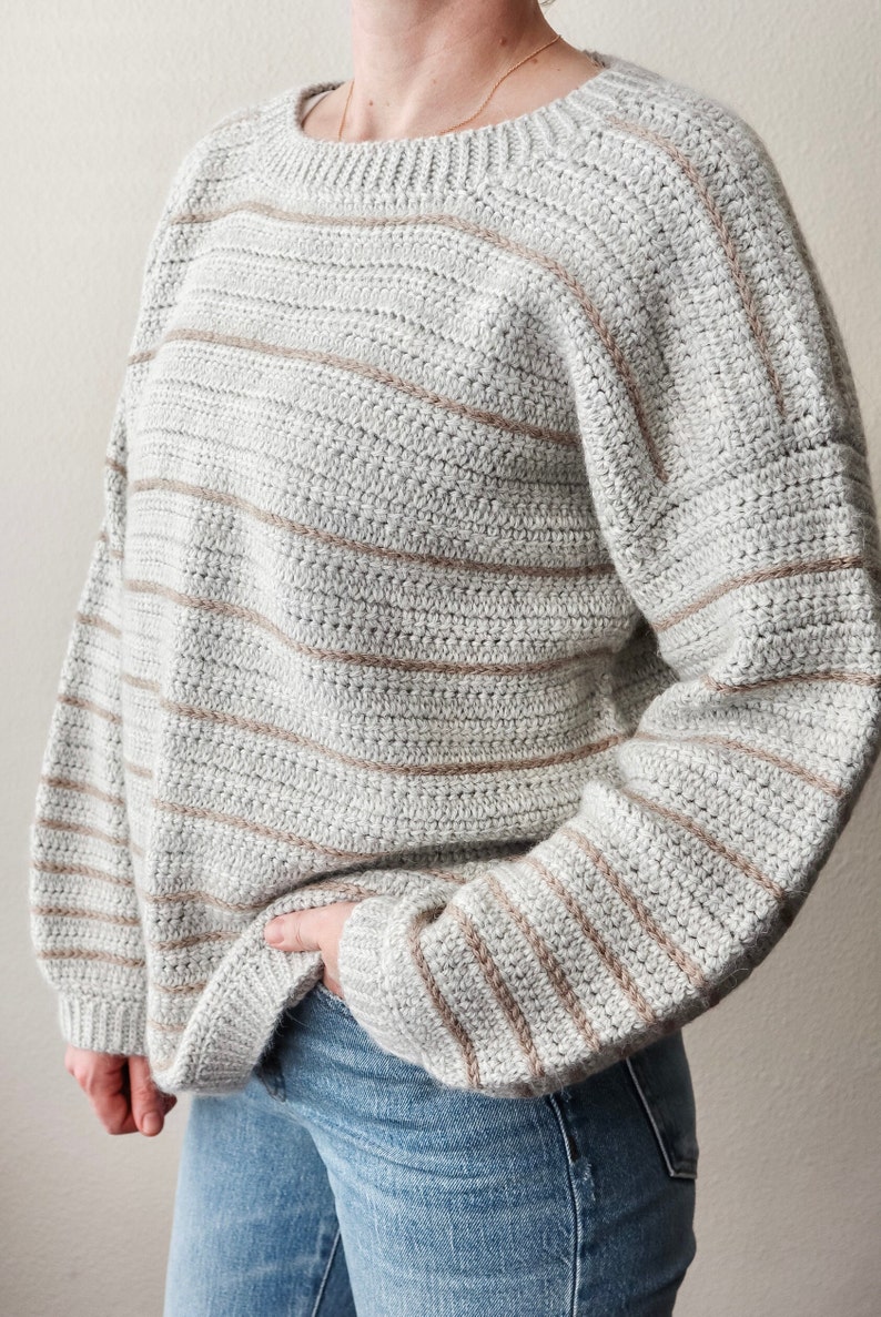May include: A grey and brown striped crocheted sweater with long sleeves.