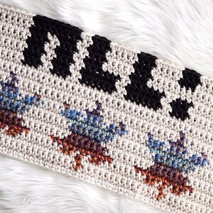 Puede incluir: Una manta de ganchillo con un patr&oacute;n geom&eacute;trico en blanco y negro en la parte superior y un patr&oacute;n multicolor en la parte inferior. La manta est&aacute; hecha con una variedad de colores, incluyendo azul, marr&oacute;n y naranja.