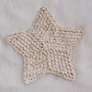 May include: A white crocheted star with gold glitter accents. The star is a handmade item and would be a great addition to a nursery or child's room.