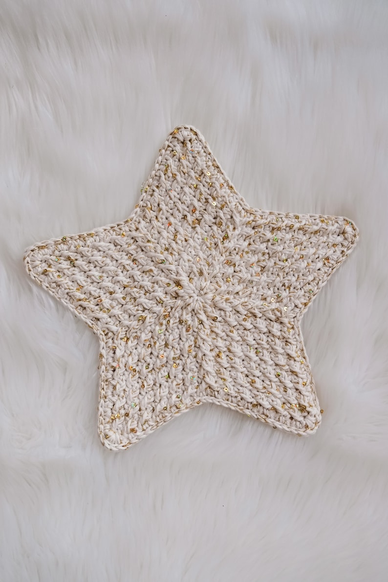 May include: A white crocheted star with gold glitter accents. The star is a handmade item and would be a great addition to a nursery or child's room.