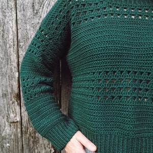 May include: A green crocheted sweater with a lacy pattern. The sweater has long sleeves and a round neckline.