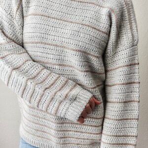 May include: A grey and brown striped sweater with long sleeves and a round neckline.