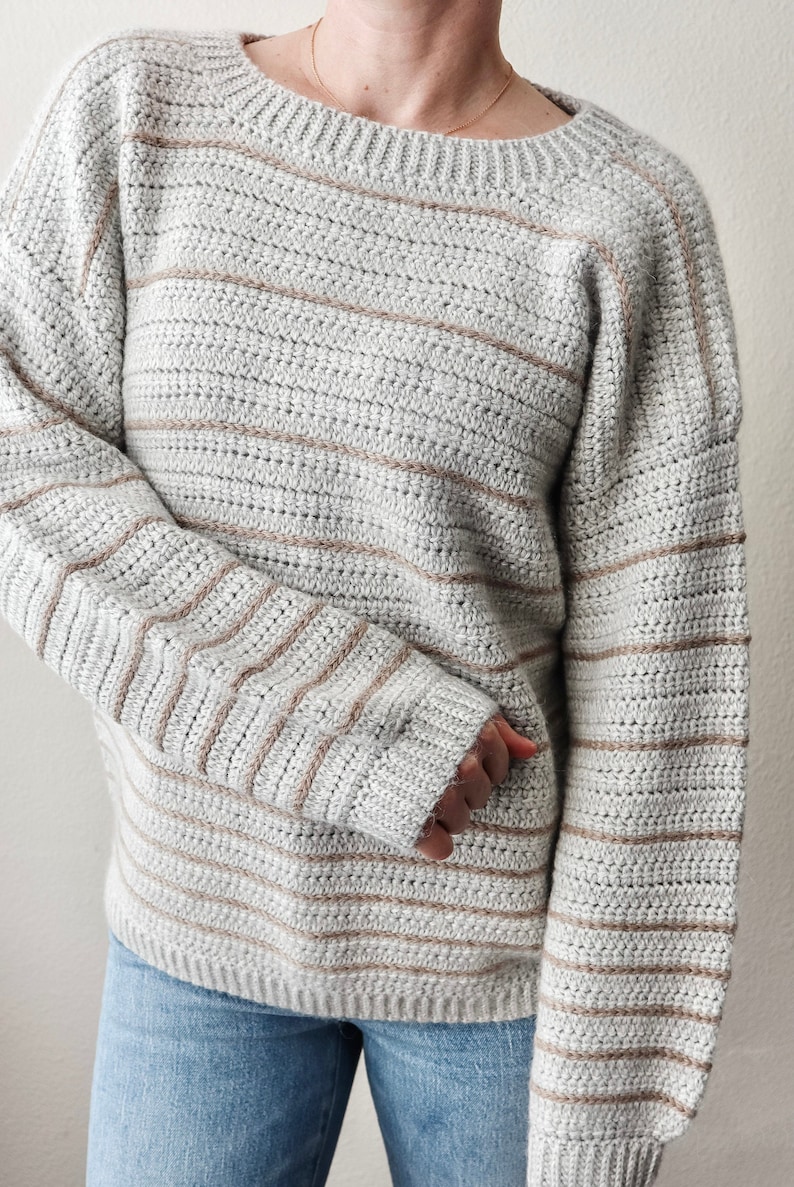 May include: A grey and brown striped sweater with long sleeves and a round neckline.