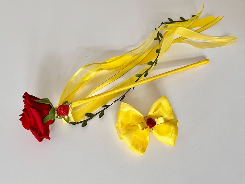 May include: A yellow wand with a red rose and green leaves at the end. A yellow bow with a red rose in the center is also included.