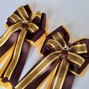 May include: Two brown and gold striped ribbon bows with a gold horse charm in the center of each bow.