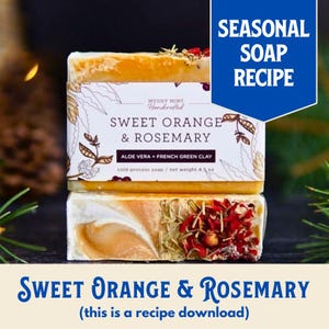 May include: A handmade soap bar with a sweet orange and rosemary scent. The soap is a light orange colour and has a label that says "Muddy Mint Handcrafted Sweet Orange & Rosemary Aloe Vera + French Green Clay Cold Process Soap / Net Weight 4.5 oz". The soap is sitting on a wooden surface.