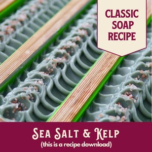 May include: Close-up of handmade soap bars with a sea salt and kelp design. The soap is a muted green color, with a wave-like pattern and sprinkled with pink salt crystals. Wooden dividers and the text "Classic Soap Recipe" are visible.