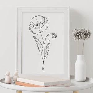 May include: A black and white line drawing of a poppy flower in a white frame on a white table with a white vase and dried flowers.