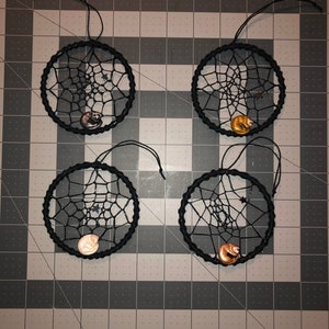 May include: Four black dreamcatchers with a white web design and a small animal charm hanging from each. The charms are a brown bear, a white bear, a brown bear, and a white bear.
