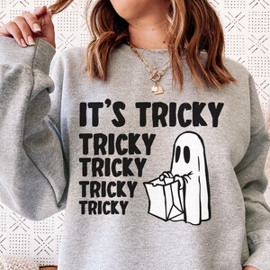 May include: Gray sweatshirt with a ghost holding a bag and the text "It's Tricky" and "Tricky" repeated four times.