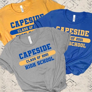 May include: Three t-shirts with the text "Capeside Class of 2001 High School" in blue and yellow. The shirts are gray, blue, and yellow.