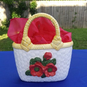May include: White ceramic basket with a yellow handle and red flower design. The basket is shaped like a handbag.