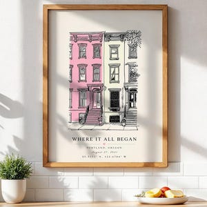 May include: A framed wall art print featuring a line drawing of three townhouses, with the left building in pink and the center in pale yellow. Text below reads WHERE IT ALL BEGAN, PORTLAND, OREGON, AUGUST 27, 2021, and coordinates 45.5152 N, 122.6784 W.