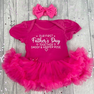 Dark pink short sleeve tutu romper with a matching bow and headband above. White love hearts design with lettering on the tutu romper saying Our First Father's Day Together Daddy & Daughter