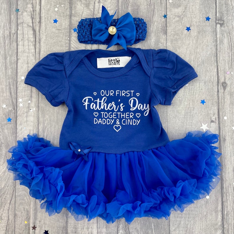 Royal blue short sleeve tutu romper with a matching bow and headband above. White love hearts design with lettering on the tutu romper saying Our First Father's Day Together Daddy & Daughter