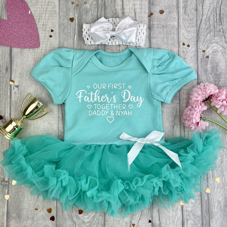 Green short sleeve tutu romper with a matching bow and headband above. White love hearts design with lettering on the tutu romper saying Our First Father's Day Together Daddy & Daughter