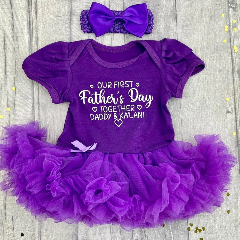 Dark purple short sleeve tutu romper with a matching bow and headband above. White love hearts design with lettering on the tutu romper saying Our First Father's Day Together Daddy & Daughter