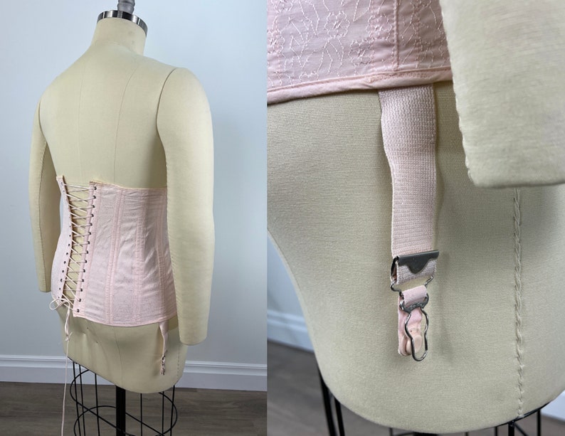 May include: A pink satin corset with a lace-up back and garter straps. The corset is on a white mannequin.