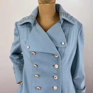 May include: A light blue double-breasted coat with silver buttons and embroidered detailing on the collar and cuffs.